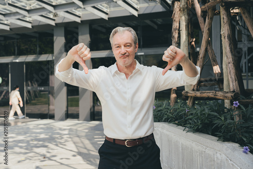 Foto Man white shirt thumbs down outdoor expression gray hair middle aged casual disp