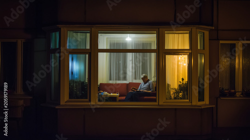 Man staring through apartment window after finishing late-night tasks ,alone man, refusal to eat, man sitting on the sofa, a man working in the evning in empty flat, sad man playin