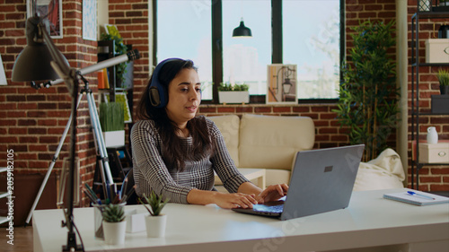 Quadro su tela Prospecting job candidate remotely being interviewed via online videocall, wearing headphones answering HR interview questions during videoconference meeting while staying at home