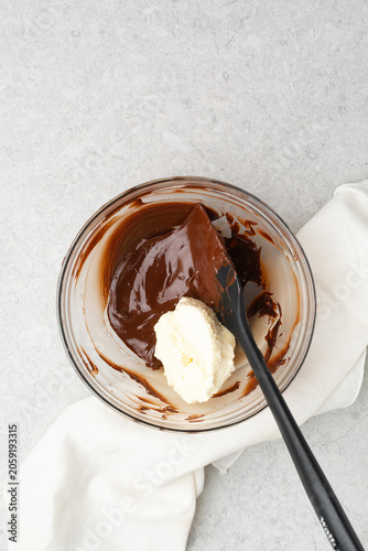 Overhead view of vanilla buttercream being mixed with melted chocolate to make chocolate buttercream, process of making chocolate buttercream or chocolate frosting