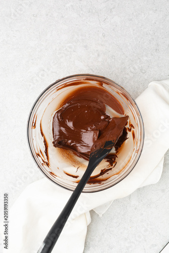 Overhead view of melted dark chocolate on a glass bowl on a white countertop, top view of melted chocolate for baking