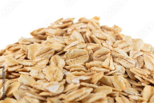 Pile of raw whole grain rolled oats on white background.