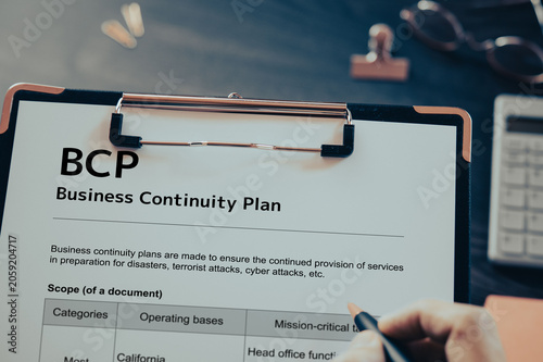 Business Continuity Plan: Realistic clipboard-up placed on  with clips, calculator, pen. Contributor-created fictional business document for illustrative purposes.