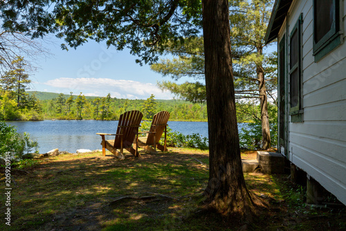 Fotografi Scenic Maine lakefront cabin with two Adirondack chairs out front