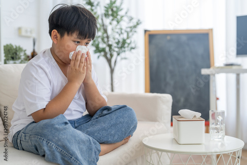 Photography Young asian boy sneezing or blowing his nose and mouth with tissue, cold allergi
