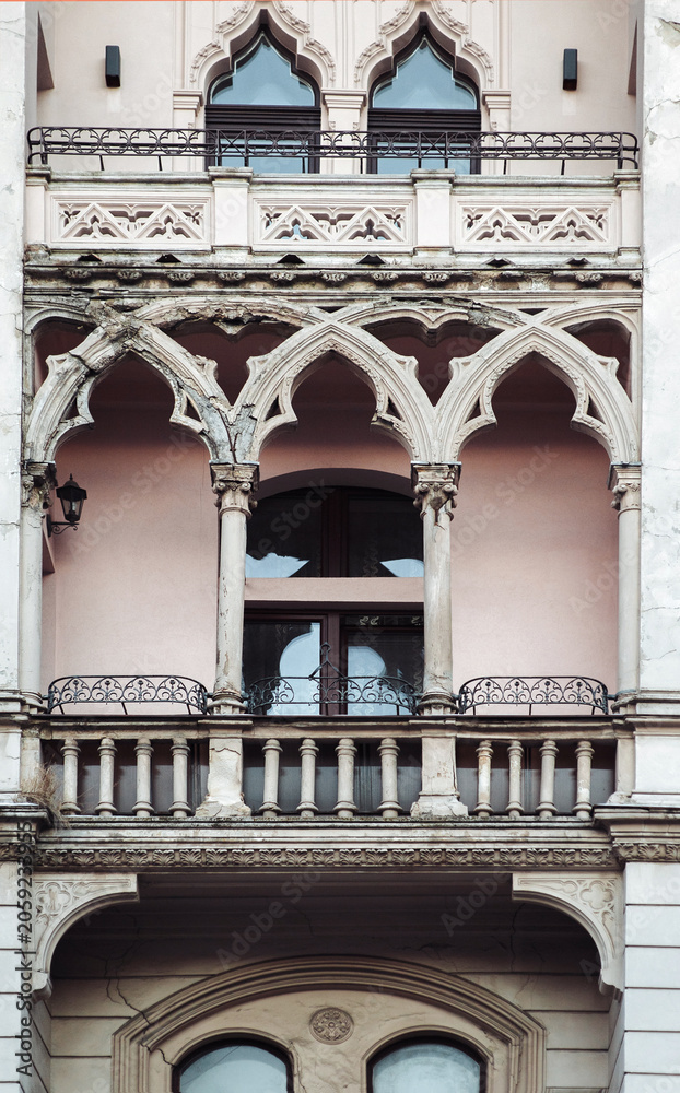 Naklejka premium Balcony and windows on the white faзade of a neoclassical building with oriental relief motifs, capitals, and decorative elements. Lviv, Ukraine.