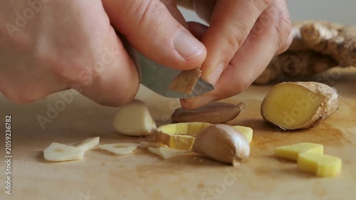 person peeling ginger sliced ginger and garlic on cutting board picking up the pieces close up.
