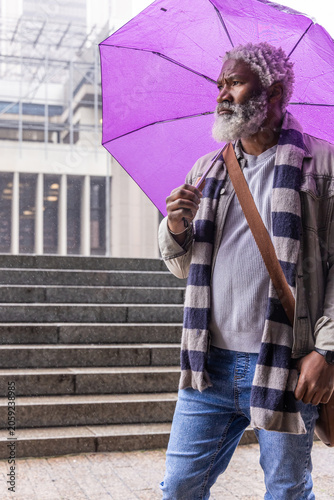 Senior African American man standing on steps outside office with purple umbrella scarf, copy space