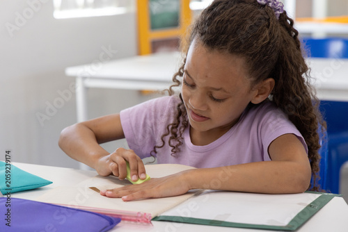 Canvas-taulu African American child student erasing in notebook using eraser at desk in class