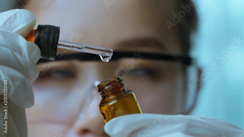 Female Scientist Inspecting Pharmaceutical Liquid Sample with Precision Dropper.  Quality inspection, laboratory precision, pharmaceutical research, healthcare science