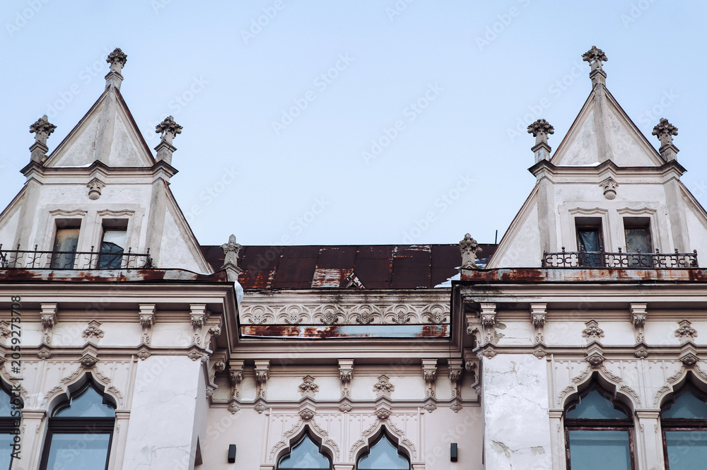 Naklejka premium Antique ornate windows and roof on the white faзade of a neoclassical building with oriental relief motifs, capitals, and decorative elements. Lviv, Ukraine.