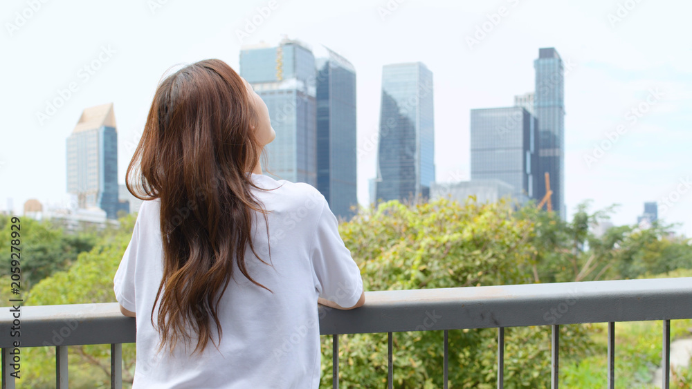 Fototapeta premium Asian Woman Looking at Bangkok City Skyline from Benchakitti Park Bridge