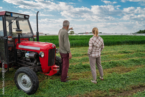 Father and daughter on their land talking next to the tractor, 