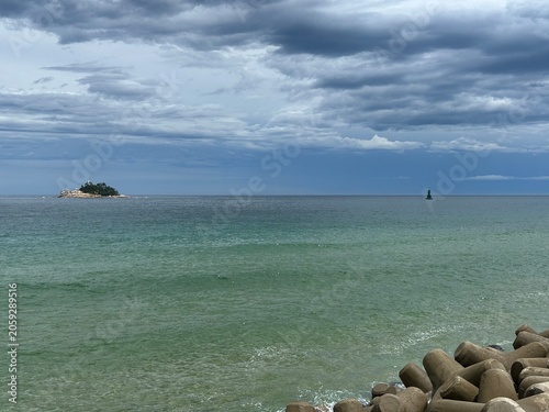 Dramatic Seascape with Small Island Under Cloudy Sky