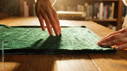 A person's hands smoothing a green fabric on a wooden table