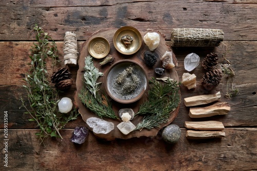 Sacred smudging tools with palo santo wood and quartz crystals on aged wood in a moody overhead shot for spiritual lifestyle and yoga branding