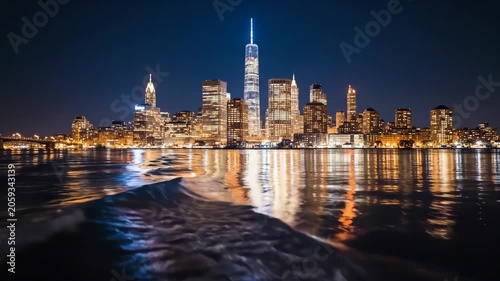 Stunning Night View of New York City Skyline with Reflecting Lights on Water.