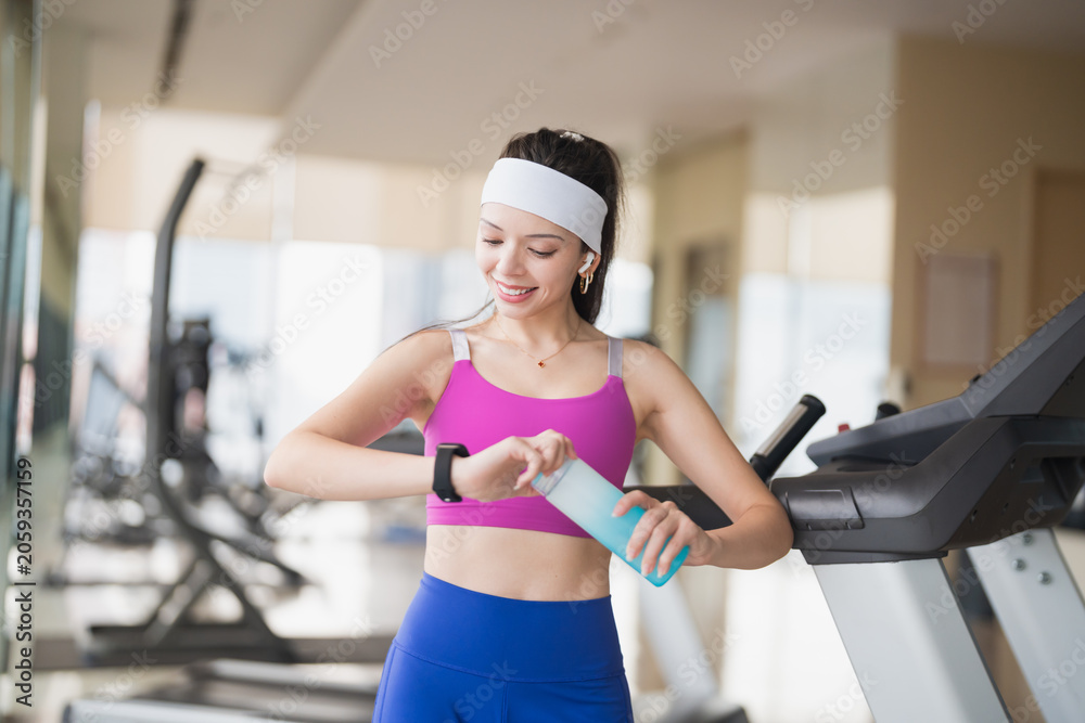 Fototapeta premium Young Hispanic Gen Z Woman in Sportswear Checking Smartwatch Health App After Gym Workout