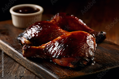 Slow smoked barbecue chicken leg quarters on a rustic wooden board