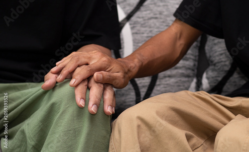 Tableau sur toile hand on hand of gay couple during sitting on sofa at home, encourage concept