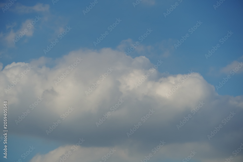 Obraz premium Fluffy white cumulus clouds drift across a clear blue sky on a bright day