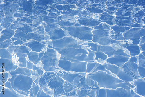 Blue swimming pool water background with bright caustic light reflections.