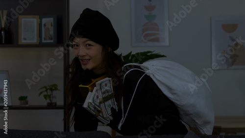 Slika na platnu Asian Female Thief in Black Beanie Holding Stacks of Cash