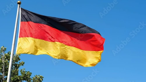 Flag of germany waving in the wind against a clear blue sky