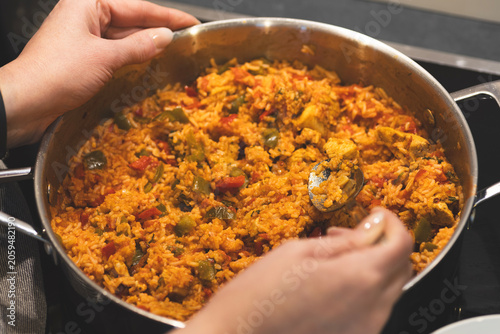 Fotografi hands serving a homemade rice dish from a cooking pot, representing creative use of leftovers and budget-friendly meal preparation