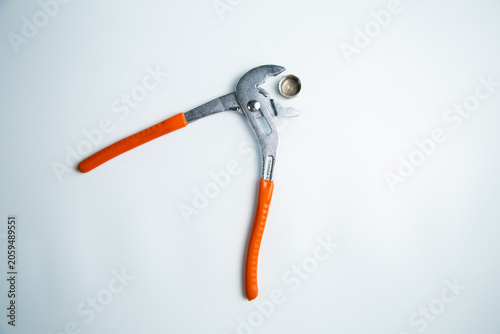 Close-up of the adjustable large wrench is open and between its teeth lies a pipe plug lying on a white background in the center. The concept of repair, plumbing, settings. High quality photo