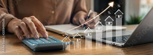 Person calculating finances with growing house value graph and laptop
