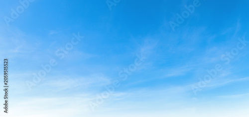 Clear blue sky with wispy clouds drifts gently above