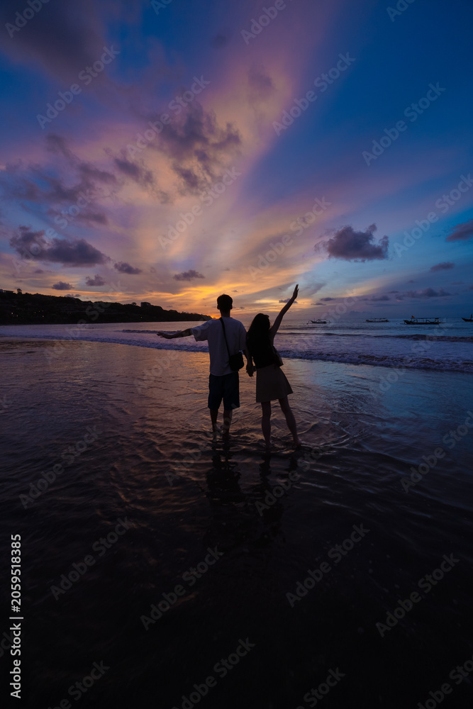 Fototapeta premium Young couple posing against a beautiful sunset sky, enjoying romantic evening atmosphere and golden hour light.