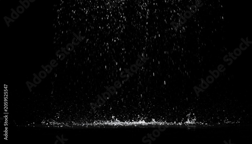 Falling water droplets illuminated against a black backdrop