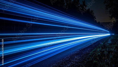 Blue light trails streak along a road through a dark forest