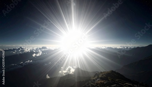 Sunburst over mountain peaks, with clouds below