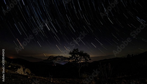 Long exposure shot of stars over a silhouette of land