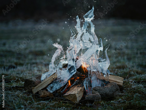 Ice flames burning on a campfire in a dark field, a surreal conceptual fusion of fire and frozen elements. Generative AI.
