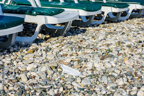 A disposable face mask discarded on pebble at the beach