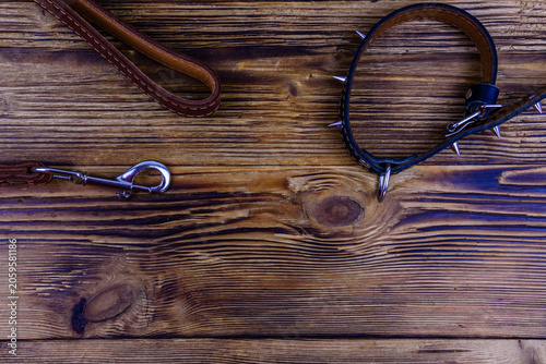 Brown leather dog leash and collar on a wooden background. Top view