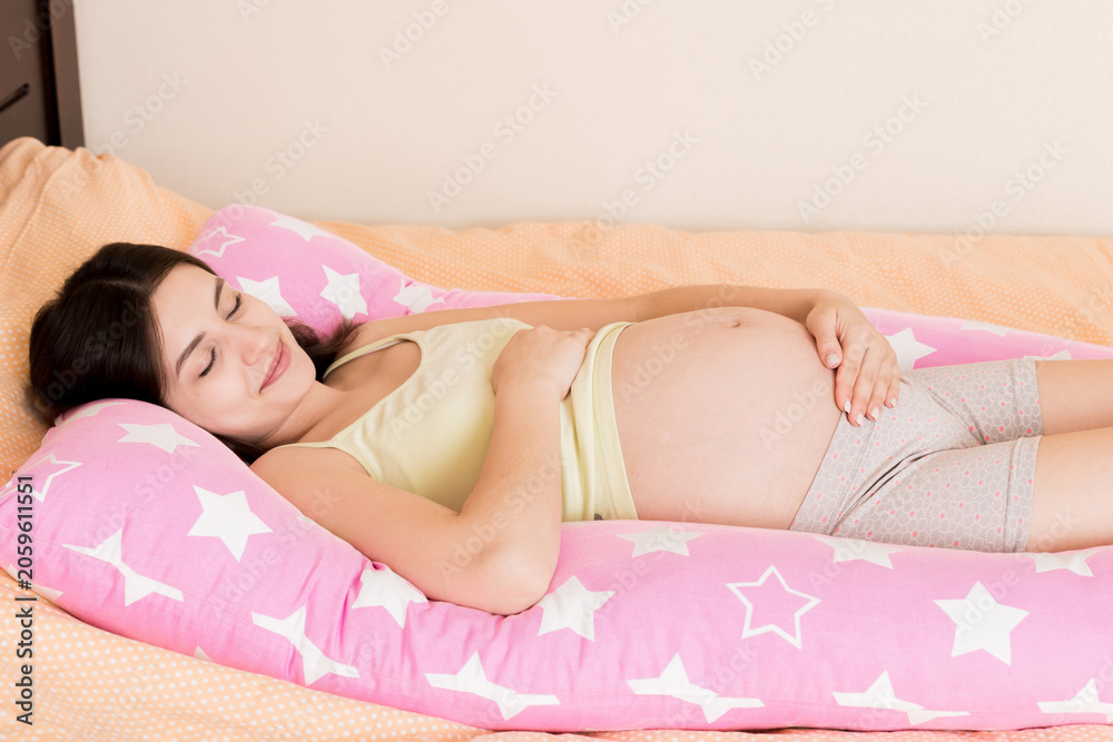 Fototapeta premium Beautiful pregnant woman sleeping with body pillow on bed