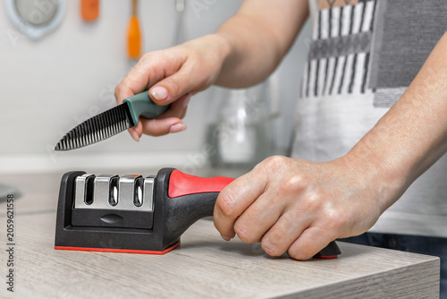 Fotografie A housewife sharpens a kitchen knife