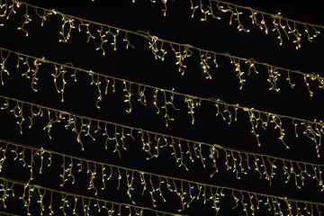 Low angle shot of multiple fairy lights hanging against the dark night sky backdrop with beautiful bokeh effect