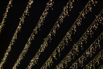 Low angle shot of multiple fairy lights hanging against the dark night sky backdrop with beautiful bokeh effect