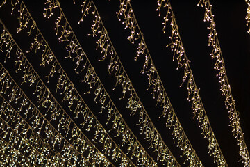 Low angle shot of multiple fairy lights hanging against the dark night sky backdrop with beautiful bokeh effect