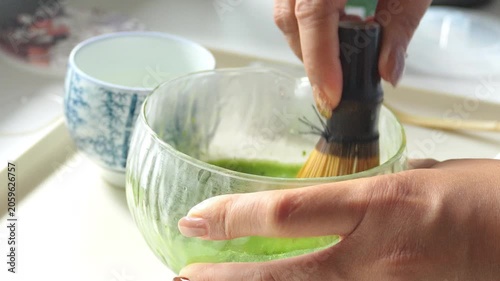 4K Traditional matcha tea preparation with bamboo whisk in ceramic bowl, Close-up of vibrant green tea being mixed Japanese culture healthy lifestyle mindfulness and wellness.