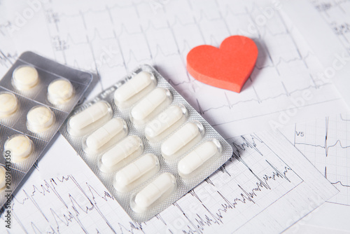 Фотография Pills in blister pack with red heart on cardiogram background