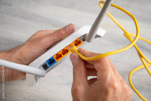 Vászonkép Man plugging internet cable into wifi router.