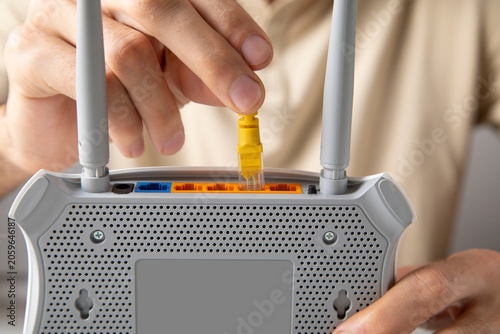 Obraz na plátně Man plugging internet cable into wifi router.