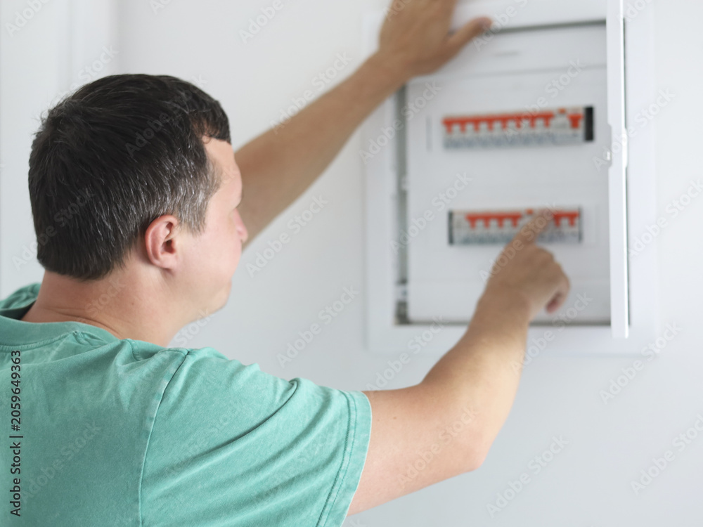 Fototapeta premium Man Technician Checking Circuit Breakers In Electrical Panel. Residential Electrical Panel Maintenance and Repair Guide